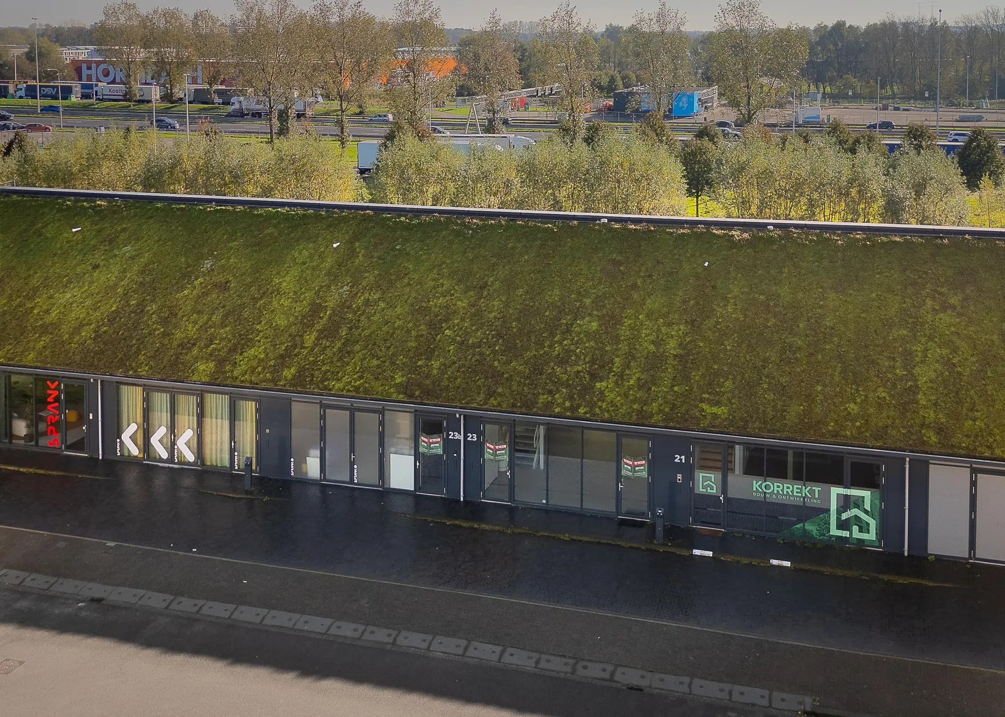 Kantoorgebouw aan de Mart Stamhof met een groen begroeid dak en zicht op omliggende snelweg en bedrijven.